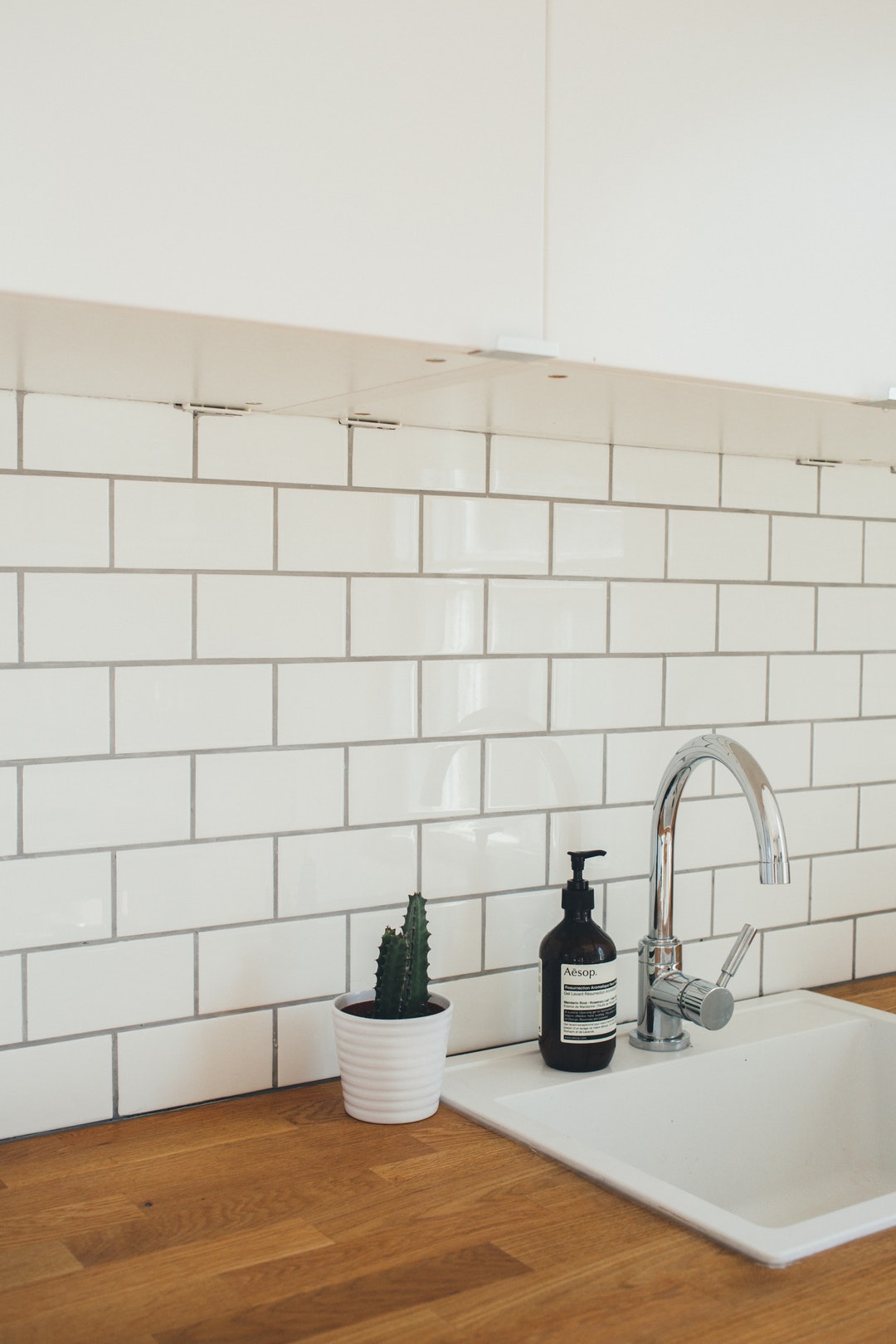 Butcher board countertops with white glass tile backsplash